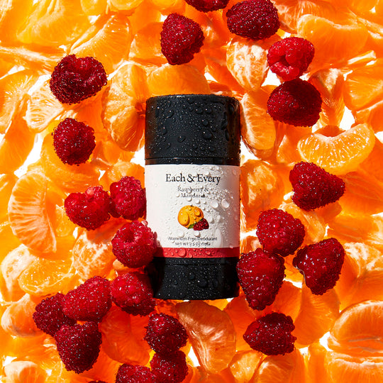 product Raspberry & Mandarin Deodorant on a bed of actual raspberries and mandarin orange sections