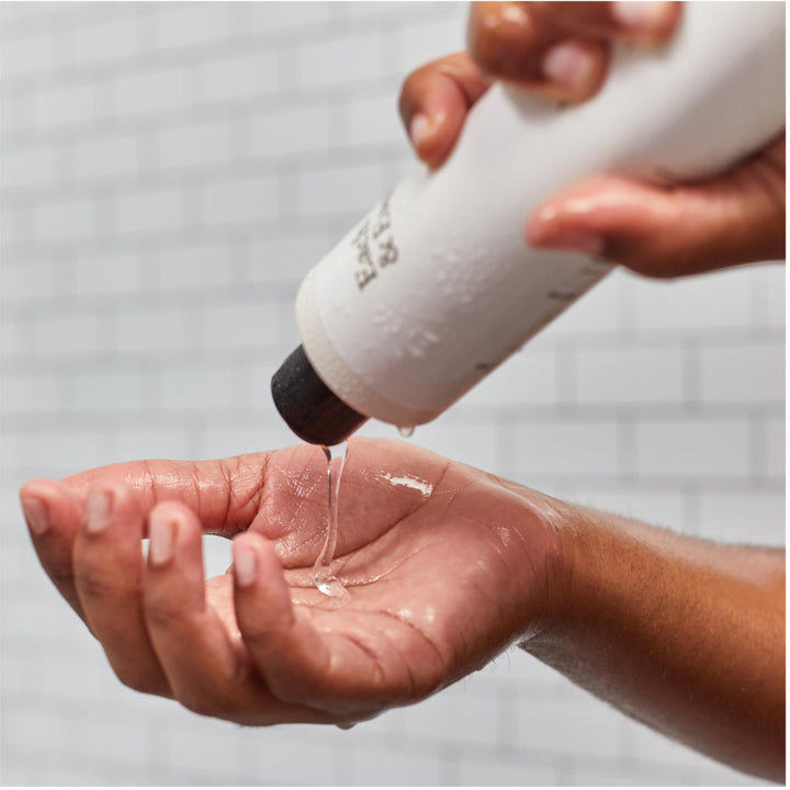 product bodywash being poured into a woman's hand in a shower
